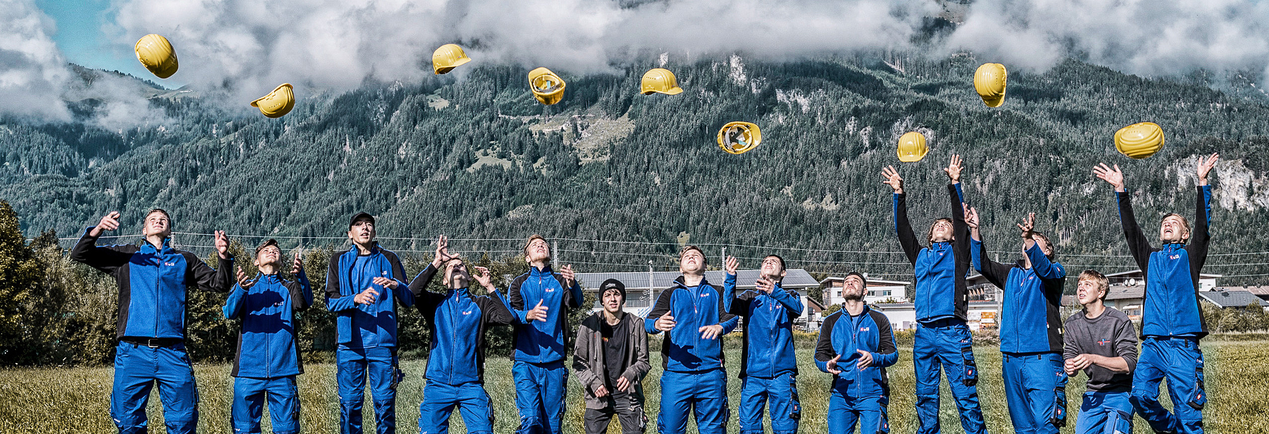 Gruppenbild Lehrlinge werfen im Freien ihre Helme in die Luft